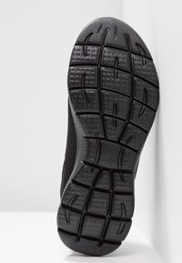 Black athletic shoe sole with textured rubber, featuring a multi-directional tread pattern for grip and stability.