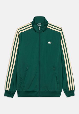 Tummanvihreä vetoketjullinen verkkatakki, jossa hihansuissa beige kolmen raidan kuvio ja pieni valkoinen Adidas-trefoil-logo rinnassa.