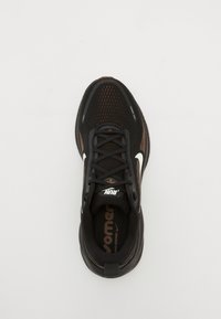 Black athletic shoe with a mesh upper, white branding, and textured accents. Features black laces and a cushioned sole for comfort.