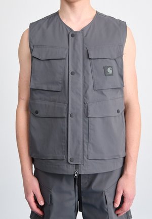 Szara bezrękawnikowa kamizelka robocza z czterema kieszeniami na zatrzaski i widocznym logo na górnej lewej kieszeni, noszona razem z dopasowanymi spodniami typu cargo.