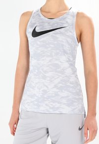 Grijze sporttanktop met een tekstuurachtige, camouflagepatroon, met een zwart Nike-logo op de borst en brede armopeningen voor ventilatie.