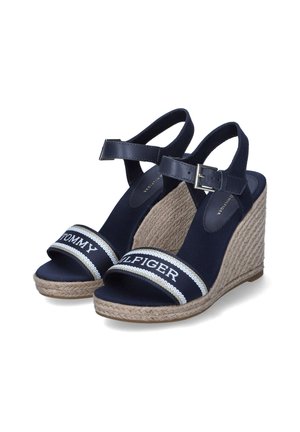 Sandelias cuñas de color marino con suela de yute trenzado, que presentan dos tiras anchas. Una de las tiras tiene el texto "TOMMY HILFIGER" en blanco, con una textura suave.