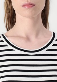 Gestreiftes Oberteil mit schwarz-weißen horizontalen Streifen, rundem Halsausschnitt mit Rippenstruktur und kontrastierendem Halsbündchen.