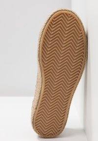 Semelle de chaussure en fibres naturelles tissées avec un motif en chevrons, dotée d'un dessous texturé et caoutchouté pour une meilleure adhérence.