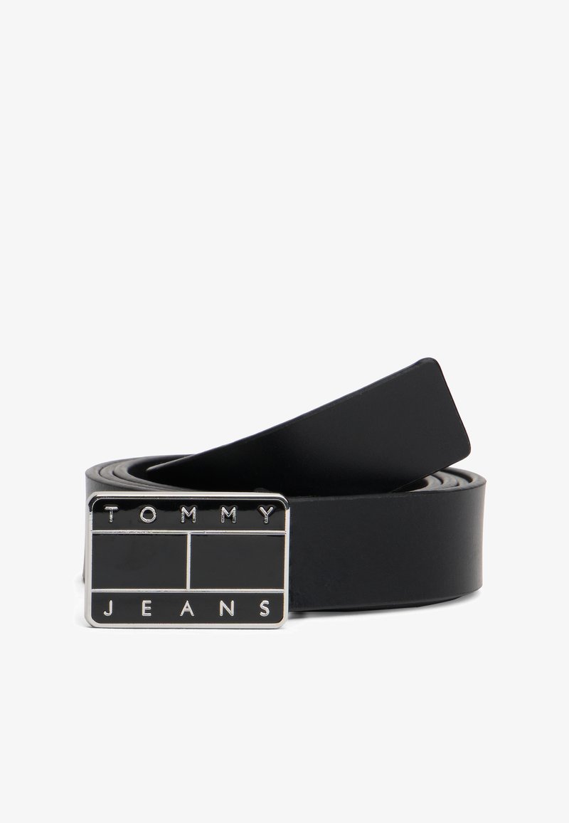 Μαύρη δερμάτινη ζώνη με ασημένια ορθογώνια αγκράφα που φέρει ανάγλυφα τα γράμματα "TOMMY" και "JEANS" σε κεφαλαία. Λείο υφή και κλασικός σχεδιασμός.