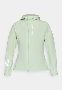 Chaqueta ajustada de color verde claro, hecha de un tejido transpirable. Presenta un cierre completo, capucha y detalles reflectantes en blanco en las mangas y el pecho.