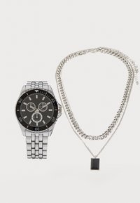 Silver metal watch with a black dial and chronograph features, paired with a silver chain necklace featuring a rectangular black pendant.