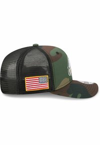 Camouflage-Baseballmütze mit einer einfarbig grünen Front, Netzrücken und einem Patch mit der amerikanischen Flagge an der Seite. Gebogener Schirm und strukturierte Form.