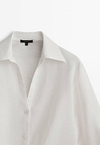 Witte linnen overhemd met een klassieke kraag, een knoopsluiting aan de voorkant en een relaxed fit. Zachte textuur en lichtgewicht materiaal zichtbaar.