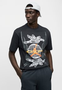 Μαύρο βαμβακερό μπλουζάκι με γραφικό σχέδιο που απεικονίζει μια γη και χέρια σε λευκό και πορτοκαλί χρώμα, στρογγυλή λαιμόκοψη, κοντά μανίκια, άνετη εφαρμογή.