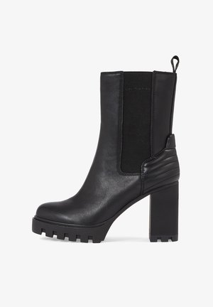 Czarny skórzany botek sięgający kostki na masywnej podeszwie, z elastycznymi bocznymi panelami, żebrowanymi akcentami i teksturowaną gumową podeszwą.