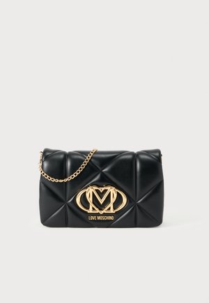 Svart vadderad väska i konstläder med guldkedjestrap, med en framträdande guldsymbol och slät yta med diamantmönster.