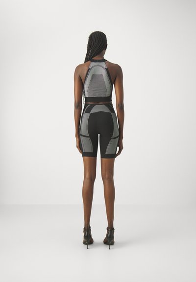Set athletic negru, format dintr-un top halter ajustat și pantaloni scurți cu talie înaltă, având panouri texturate și modele contrastante pe un material respirabil.