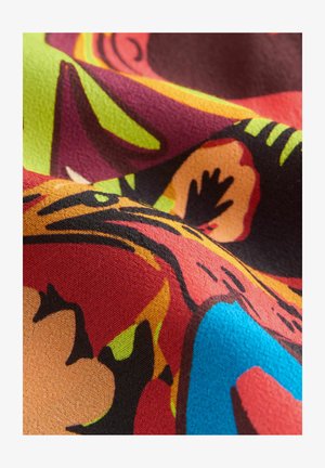 Többszínű textil, amely élénk virágmintákat ábrázol piros, narancssárga, zöld és kék színekben fekete háttéren; a texturált felület mélységet ad a mintának.