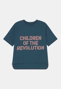 T-shirt azul-petróleo de manga curta com mangas raglan. Apresenta texto em rosa: "FILHOS DA REVOLUÇÃO." Ponto arredondado na bainha com detalhe de fecho lateral.