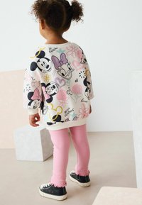 Lastele sobiv ühis suuruses kapuutsiga sweatshirt, millel on värvilised Minnie ja Mickey Mouse'i prindid, koos roosa ribaga retuuside ja mustade kingadega, millel on volangiga sääred.