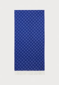 Coperta blu con un motivo geometrico, bordi frangiati, texture tessile soffice e accenti azzurri a contrasto.