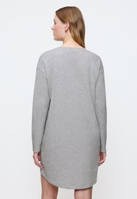 Szara bawełniana sukienka z długimi rękawami i okrągłym dekoltem. Miękka tekstura, luźny krój i boczne rozcięcia przy hemie. Prosty wzór z tyłu.