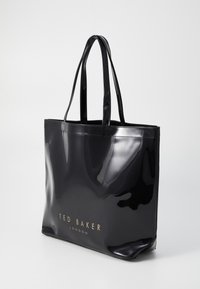 Svart, glansig tote-väska med dubbla handtag, med en logotyp i guldtryck framtill. Slät textur med rektangulär form.