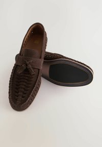 Brune ruskind loafers med vævet detaljer på overdelen, flad gummisål og accenttråd omkring kanten. Ingen synlig branding.