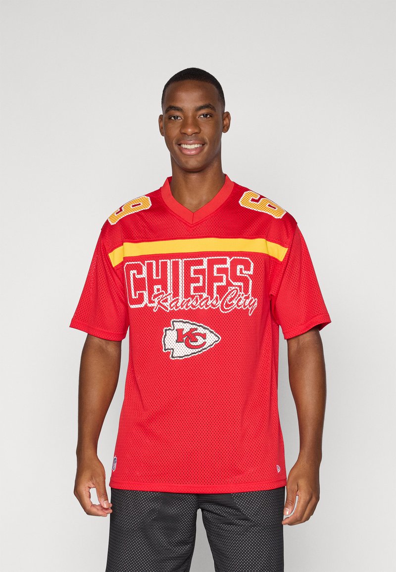 Piros hálós focimez sárga kiegészítőkkel, "CHIEFS Kansas City" fehér hímzéssel, 69-es szám a vállakon, rövid ujjú, V nyakú kialakítással.