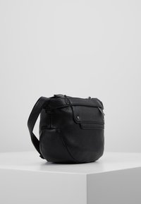 Borsa a spalla in pelle nera con finitura testurizzata, dotata di tracolla e tasca frontale, forma compatta e dettagli in metallo.