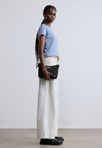 Cămașă cu mâneci scurte, bleu deschis, pantaloni albi cu picioare largi, pantofi negri și o poșetă neagră matlasată cu fermoar. Design simplu și curat.