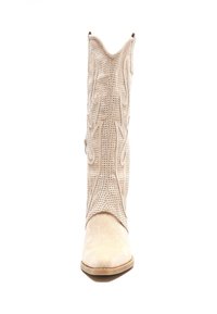 Bota de cowboy beige con cuero texturizado, costuras decorativas, punta afilada y un talón ligeramente elevado. Presenta detalles perforados en el tubo.