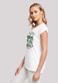 Hvitt bomulls-T-skjorte med rullede ermer, med en grønn grafisk trykk på fremsiden, og en løs passform. Kombiner den med lyse jeans.