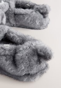 Graue Hausschuhe aus Kunstfell mit einer weichen, flauschigen Textur und runden Zehen. Sie verfügen über ein schlichtes, sauberes Design ohne sichtbare Beschläge.