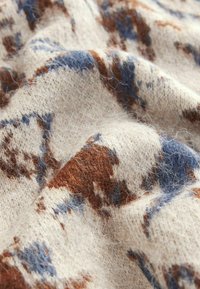 Woolen fabric with a soft texture, featuring an abstract pattern in brown and blue on a cream background, showcasing visible fibers.