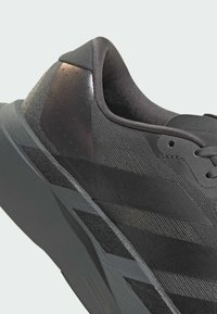 Czarne sportowe buty charakteryzują się teksturowaną cholewką z gładkimi akcentami, dwoma ciemniejszymi paskami oraz solidną gumową podeszwą, co zapewnia elegancki design.