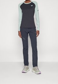 Dlouhý rukáv košile v tmavě šedé barvě se světlými mátovými rukávy, doplněná tmavě šedými kalhotami a světlými šedými teniskami s fialovými akcenty.