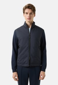 Navy zip-up jacket with a high collar, ribbed cuffs, and side pockets. Smooth, durable fabric with a minimalist design.