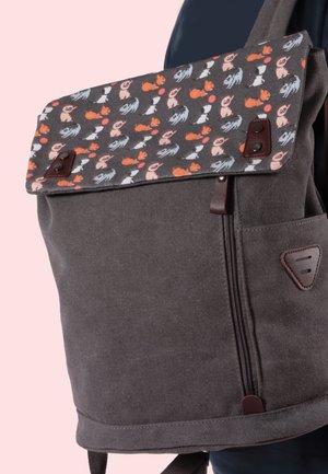 Grauer Canvas-Rucksack mit einer Klappe, die ein buntes, sich wiederholendes Muster aus kleinen Cartoon-Hunden in verschiedenen Posen zeigt.