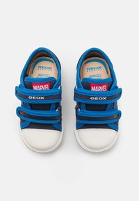 Sneakers blu con una tomaia in tessuto traspirante, punta in gomma bianca e cinturini in velcro. Presentano i loghi "MARVEL" e "GEOX".