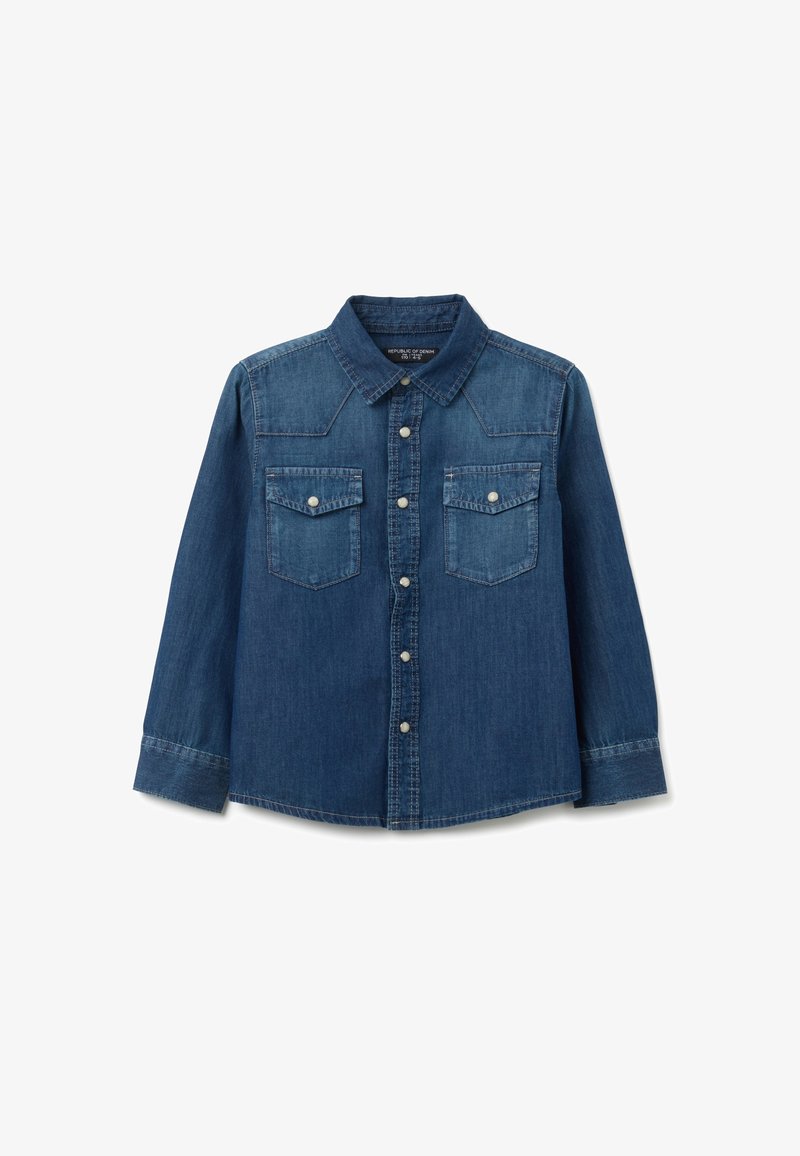 Camisa de mezclilla azul de manga larga con botones en la parte delantera y dos bolsillos en el pecho con botón, colocada sobre un fondo blanco.