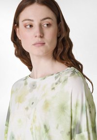 Lätt, blommig topp med grön och vit färgskala, rund halsringning och lös passform. Mjuk, flytande tyg.