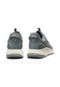 Szare trampki z materiałów skórzanych i siateczkowych, z teksturowaną podeszwą, pętelką do zakładania oraz subtelnymi akcentami logo na pięcie.
