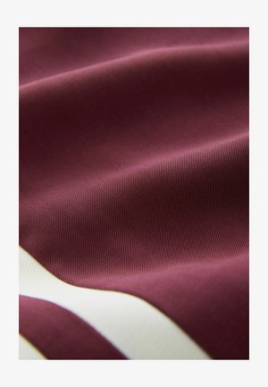 Burgunderroter Stoff mit glatter Textur und wellenförmigen weißen Streifen. Das Material wirkt leicht und leicht glänzend.