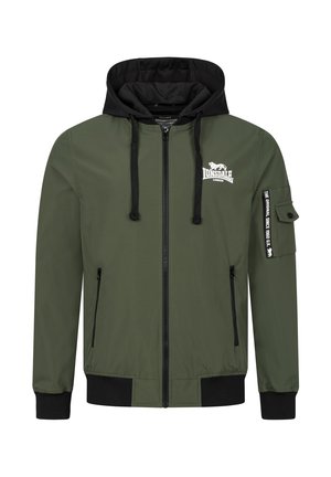Zelena bomber jakna s crnom kapuljačom. Ima prednji zip, bočne džepove i zakrpu na rukavu. Mekan, glatki tekstil.