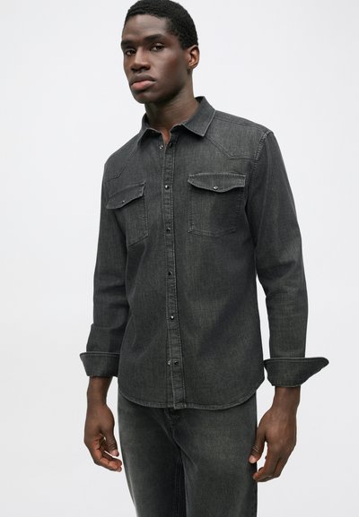 Dark gray denim shirt with long sleeves, button front, two chest pockets, and folded cuffs. Smooth texture and classic design.