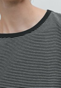 Black and white striped top with a round neckline. Soft cotton texture, featuring even horizontal stripes and a black trim at the neck.