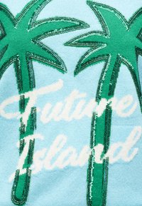 Δύο πράσινες φοίνικες με παγιετένια περιγράμματα σε ανοιχτό γαλάζιο ύφασμα, που καλύπτουν μερικώς λευκό κείμενο με καλλιγραφική γραμματοσειρά που λέει «Tropical Island».