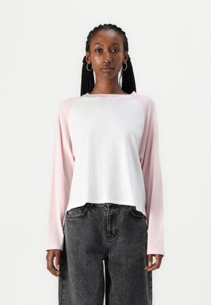 Langarmshirt mit einem weißen Körper und hellrosa Raglanärmeln. Hergestellt aus weichem Stoff, mit einer lässigen Passform und rundem Ausschnitt.