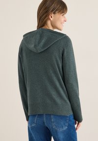 Kapuzensweatshirt in Dunkelgrün, aus weichem Strickstoff gefertigt, mit einem gerippten Saum und Bündchen für zusätzliche Textur.