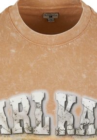Kortærmet, falmet fersken T-shirt med rund hals, der har et sprækket hvidt grafisk tekstdesign på forsiden. Blød, tekstureret stof.
