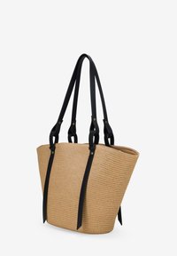 Bolso de paja trenzada con asas de cuero negro, que presenta una apertura amplia y un diseño estructurado y angular para proporcionar estabilidad.