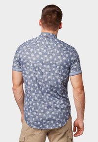 Camicia a maniche corte blu con motivo, dalla texture leggera, caratterizzata da disegni bianchi a forma di foglia e una fascia del colletto a contrasto. Vista posteriore mostrata.