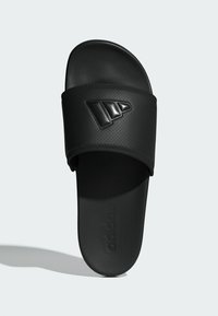 Black slide sandal with a textured synthetic upper, featuring a prominent black three-stripe logo. Flat sole with brand text embossed.
